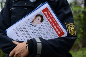 Eine Polizeibeamtin hält am Fundort ein Flugblatt mit einem Foto des getöteten achtjährigen Jungen in den Händen.  Foto: dpa