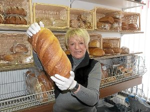 Gisela Reberg präsentiert ein Brot aus dem Tafelladen. Offene Lebensmittel werden nur mit Hygiene-Handschuhen angefasst.  Foto: Dürr