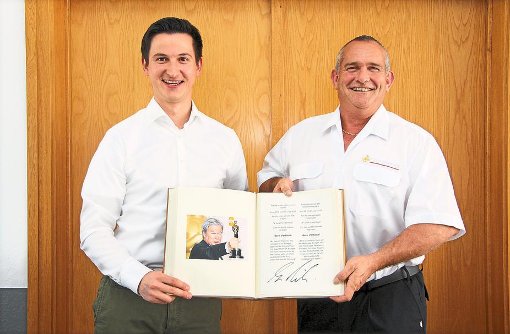 Bürgermeister Roman Waizenegger (links) und Kommandant Dieter Fecker zeigen stolz den Eintrag von Regisseur Gore Verbinski ins Goldene Buch der Gemeinde. Foto: Wahl