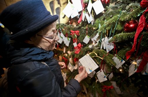 Eine Frau liest eine  Karte  am Weihnachtsbaum im Rathaus. Hier hängen die Wunschzettel von 1500 Kindern Foto: Peter Petsch