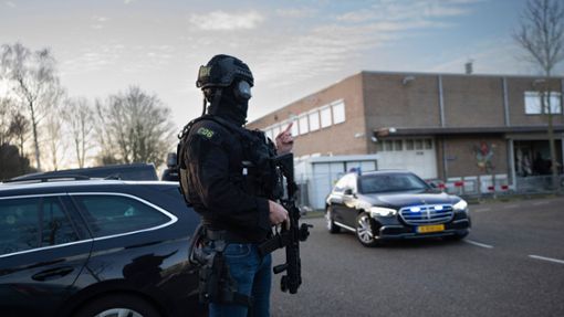 Maskierte und bewaffnete niederländische Polizisten bewachen einen Transport mit einigen der Verdächtigen, die vor dem Hochsicherheitsgebäude des Gerichts in Amsterdam eintreffen. Foto: Peter Dejong/AP/dpa