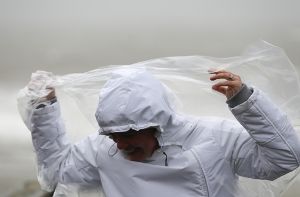 Eine Frau versucht auf Sylt (Schleswig-Holstein) im Wind ihr Regencape festzuhalten. Orkantief Xaver erreicht die deutsche Nordseeküste. Foto: dpa