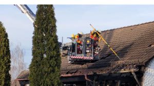 Die Feuerwehr entfernt Ziegel vom Dach, da Dachlatten in Brand geraten waren. Foto: Hezel