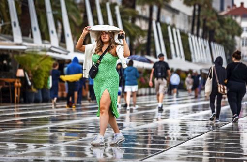 Eine junge Frau in Split schützt sich auf ihre Weise vor dem Regen. Foto: imago//Zvonimir Barisin
