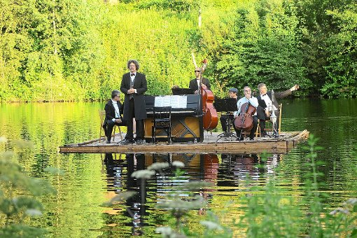 Das tief ins Wasser eintauchende Floß samt Musikern und Instrumenten an der idyllischen Nagoldtalsperre Foto: Adrian Foto: Schwarzwälder-Bote
