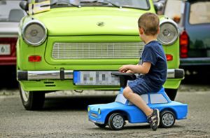 Ein kleiner Junge fährt auf einem Spielzeug-Trabant am Original vorbei. Foto: dpa