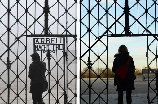 Eine Frau (links) geht 2012 durch das Tor zum ehemaligen Konzentrationslager in Dachau, auf dem Arbeit macht frei steht. Am Haupteingangstor fehlt Anfang November 2014 die Tür. Unbekannte haben die historische Tür gestohlen. Foto: dpa