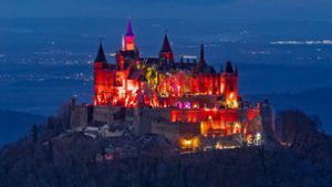 Ein Farbenspektakel: Die Burg Hohenzollern leuchtet nachts derzeit rot. Foto: Roland Beck