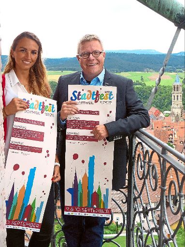Eva Moosmann und Marco Schaffert vom Kultur- und Sportamt der Stadt Rottweil präsentieren auf dem Hochturm das Plakat des Stadtfestes  im Jahr der Türme.  Foto: Stadt Rottweil