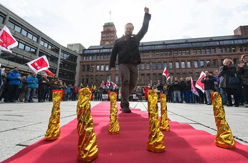 Ein Angestellter der Albert-Ludwigs-Universität Freiburg läuft am Mittwoch in Freiburg bei einer Verdi-Protestaktion über einen symbolischen roten Teppich. Foto: dpa