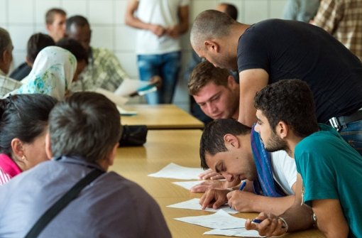 Flüchtlinge  in einer Erstaufnahmeeinrichtung in Eisenhüttenstadt (Brandenburg) bekommen Hilfe beim Ausfüllen von Formularen. Foto: dpa