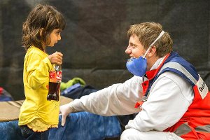 Ein freiwilliger Helfer des Deutschen Roten Kreuzes spielt in einer Notunterkunft für Flüchtlinge in Rottenburg mit der kleinen Zena aus Syrien. Foto: Kastl
