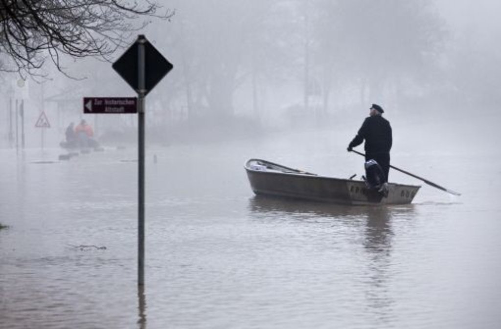 Ein Mann in einem Fischerboot paddelt am Montagmorgen in Wertheim über die überflutete Straße am Mainufer.