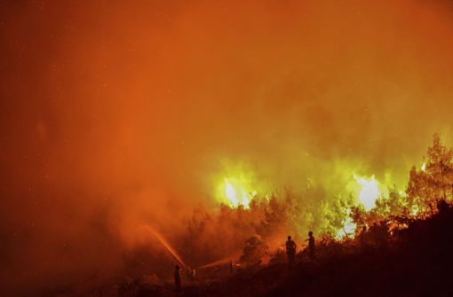 Feuerwehrleute richten Wasserstrahlen aus Feuerwehrschläuchen auf einen Waldbrand im  Pentadaktylos-Gebirge, Nord-Zypern. Foto: AP/dpa/Nedim Enginsoy