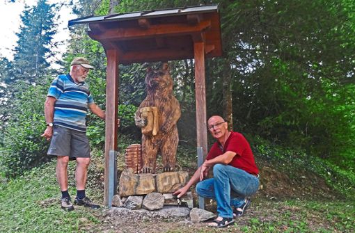 Berthold Roth (links) und Vorsitzender Hans Armbruster von den Wolftal-Imkern haben den von Simon Echle kunstfertig geschnitzten Honigbären am Steigfelsen aufgestellt. Foto: Haas