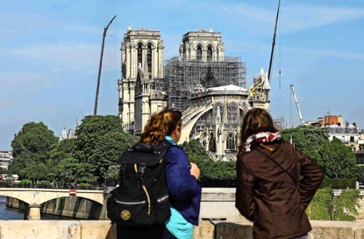 Zwei Frauen betrachten in Paris die bei einem Brand schwer geschädigte Kathedrale von Notre-Dame. Foto: AFP