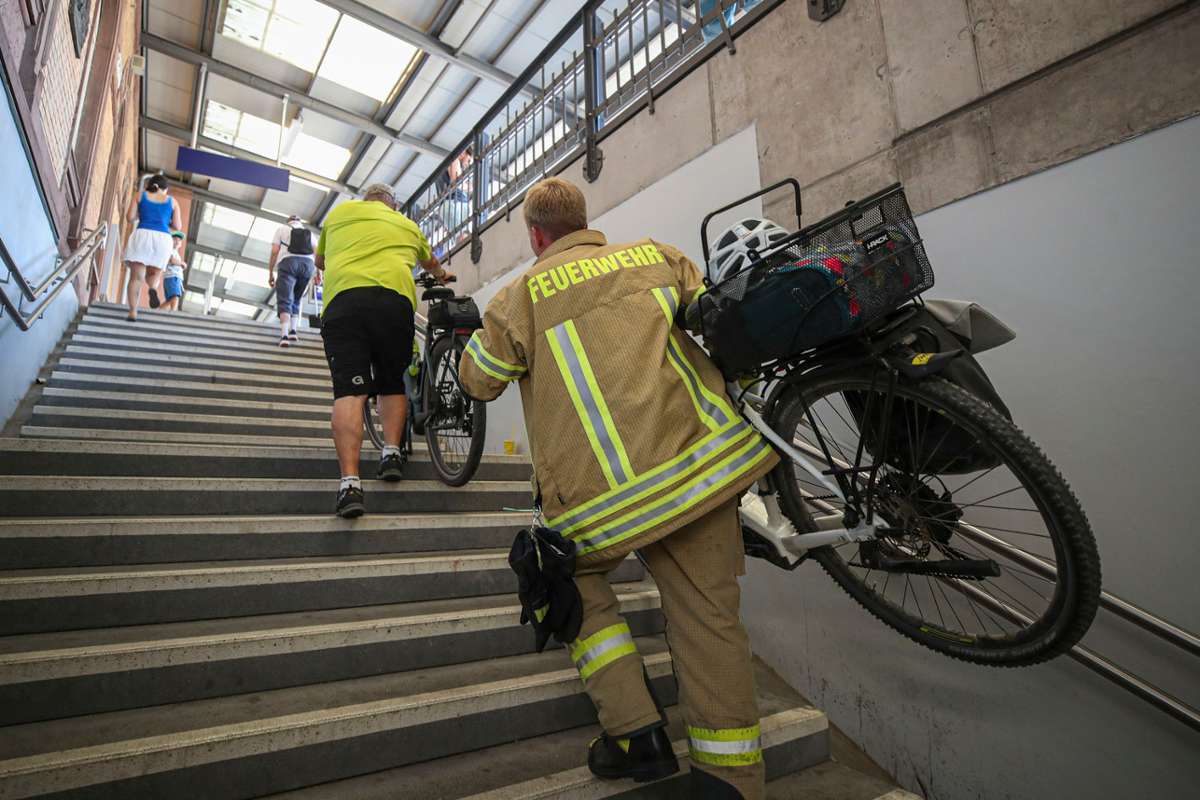 Die Feuerwehr hilft den Fahrgästen beim Schleppen der Räder, nachdem der Aufzug ausgefallen war.  Foto: Eich