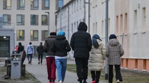 Asylsuchende gehen über das Gelände der Zentralen Erstaufnahmeeinrichtung für Asylbewerber des Landes Brandenburg in Eisenhüttenstadt. Foto: Patrick Pleul/dpa