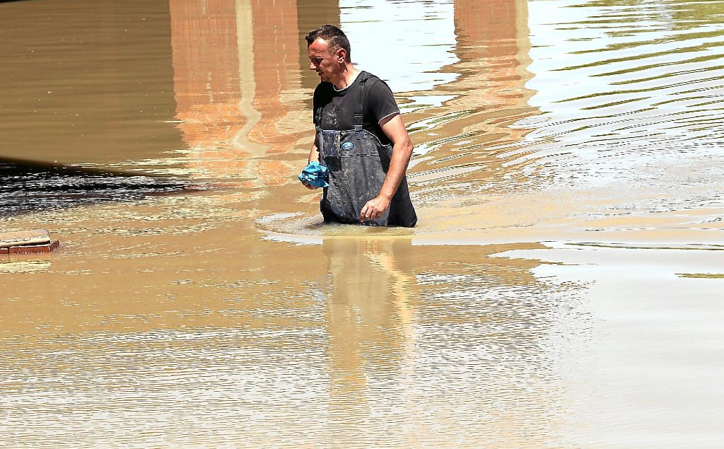 Tausende Menschen haben in Bosnien und Herzegowina durch  Unwetter  ihren gesamten Besitz verloren. Dieser Mann watet durch hüfthohes Wasser und schaut, ob noch etwas zu retten ist.