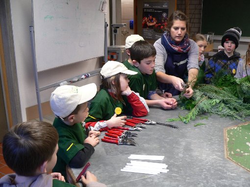 Floristiklehrerin Sarah Siegle schneidet mit den Minigärtnern Nadelzweige zu. Foto: Schumacher Foto: Schwarzwälder-Bote