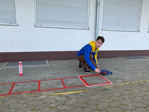 Der 19-jährige Florian Blank malt einen Teil des Fitnessparcours vor das Vereinsheim des VfL Ostdorf. Der Parkour ist sein persönliches FSJ-Projekt. Foto: Frey