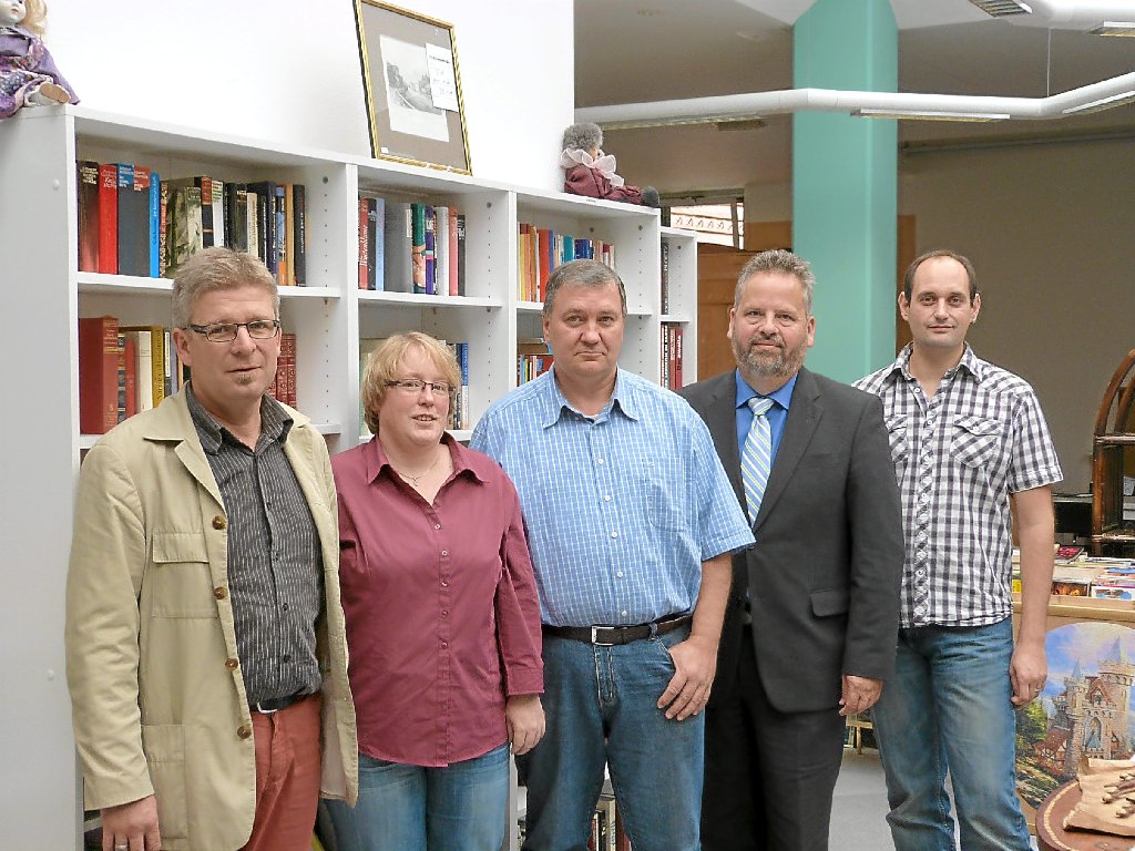 Wolfgang Sartorius (Zweiter von rechts), Michael Marxhausen (rechts) und Wolfgang Günther (links) mit zwei Langzeitarbeitslosen vor Büchern, die in der Kommode gekauft werden können. Foto: Bronner