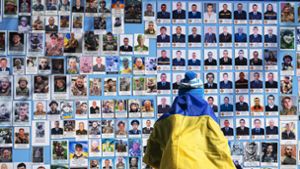 Eine Frau steht in Kiew vor einer Gedenktafel mit Fotos gefallenere Soldaten. Foto: dpa/Andrew Kravchenko