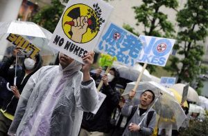 Proteste unter Regenschirmen: In Japans Katastrophengebiet gibt es derzeit heftige Regenfälle. Foto: dpa