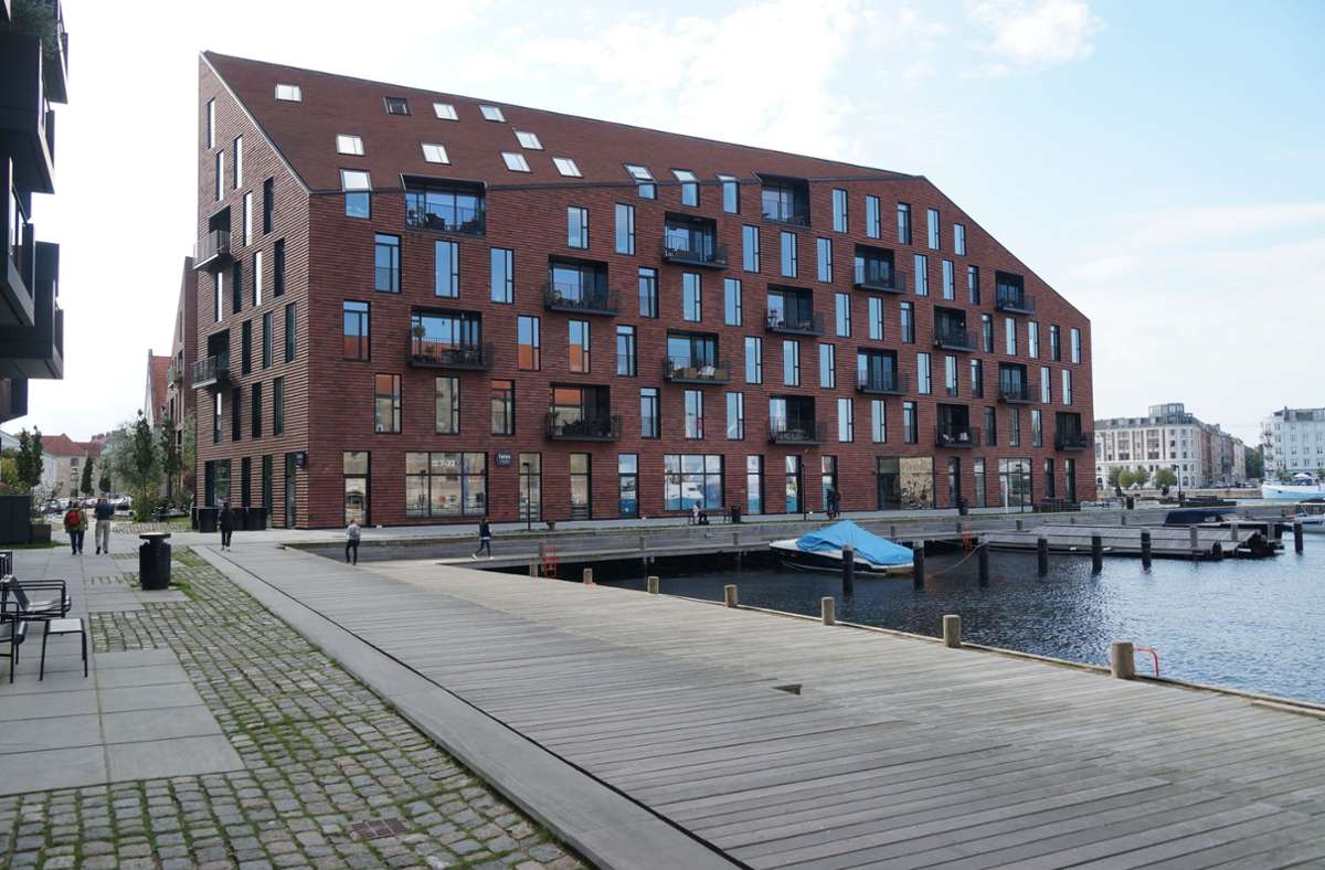 Homogene Gebäudehülle bei dem Wohnen am Hafenbecken in Kopenhagen mit Backsteinfassade, raumhohen Fenstern und Loggien. Im Erdgeschoss befinden sich auch Läden und Restaurants.
