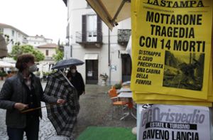 Menschen an einem  Zeitungskiosk in Stresa, an dem eine Zeitung mit der Schlagzeile „Mottarone-Tragödie mit 14 Toten“ ausgehängt ist. Foto: dpa/Antonio Calanni