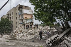 Rettungskräfte stehen auf den Trümmern eines Wohnblocks nach einem Raketeneinschlag in der Region Donezk in der Ostukraine. Foto: dpa/Nariman El-Mofty