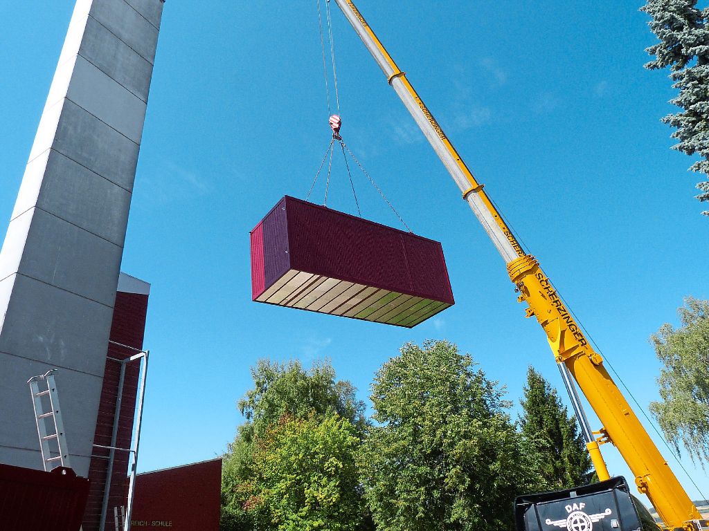 Der erste Container mit dem Treppenhaus und einem Gewicht von rund acht Tonnen schwebt hoch in der Luft.