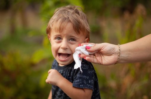 Das Kind wird im Gesicht eifrig mit einem Feuchttuch abgewischt. Foto: IMAGO/Pond5/IMAGO/xadamrx