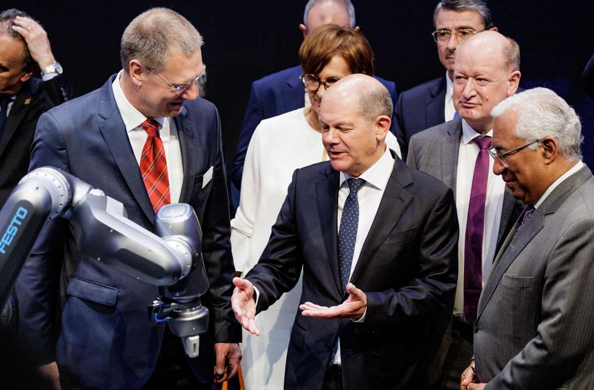 Bundeskanzler Olaf Scholz (Mitte) lässt sich am Festo-Stand von Vorstandschef Oliver Jung (links) einweisen. Portugals Premier Antonio Costa (rechts) sieht zu. Foto: AFP/AXEL HEIMKEN