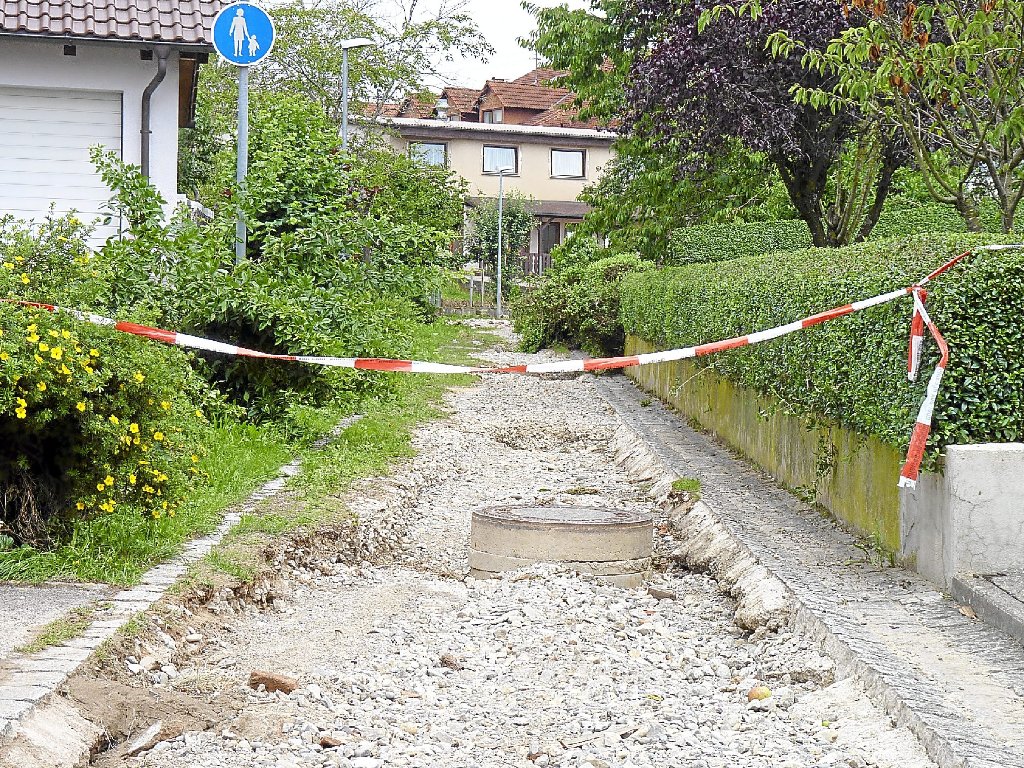 Die Schäden am Fußweg zwischen Kardinal Bea- und Schulstraße zeigen die Urgewalt des Hochwassers: Ein Schacht wurde auf gut 40 Zentimeter Tiefe freigelegt, eine Ligusterhecke auf mehrere Meter niedergedrückt (hinten, Bildmitte).