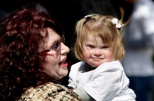 Eine Mutter hält ihr Kind mit Down-Syndrom im Arm. Foto: EPA