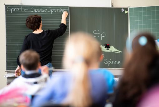 Eine Lehrerin schreibt im Klassnzimmer mit Kreide an die Tafel. Im Zollernalbkreis wird es nach Angaben der GEW zum neuen Schuljahr zu wenige Pädagogen geben. Foto: dpa