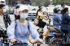 Menschen in Wuhan tragen Mund-Nasenbedeckungen, während sie zur morgendlichen Rush Hour im Stadtverkehr. (Archivbild) Foto: dpa/kyodo