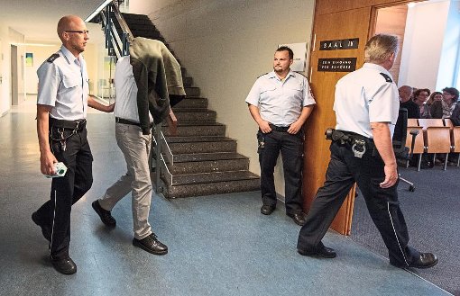 Ein Wachtmeister führt den Stiefvater von Alessio in den Gerichtssaal. Foto: Seeger