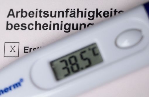 Ein Fieberthermometer liegt auf einer Arbeitsunfähigkeitsbescheinigung (gestellte Szene). Foto: dpa/Marijan Murat