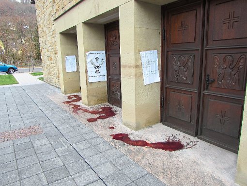 Am Kircheneingang hängen Protestplakate mit Sprüchen, der Boden ist mit roter Marmelade verschmiert:  Die Polizei ermittelt. Foto: sb