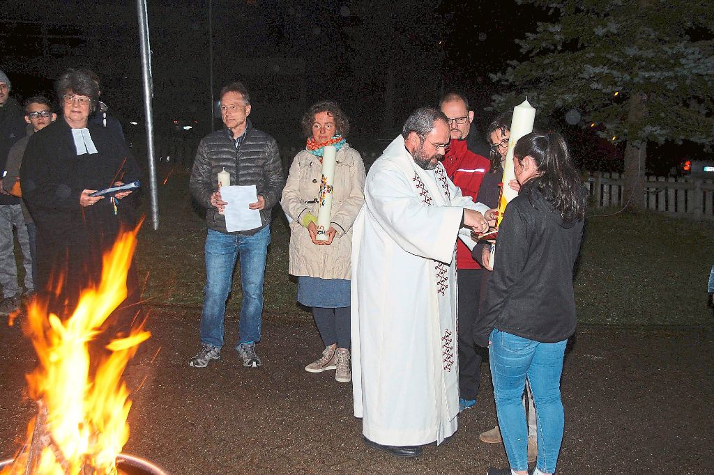 Pfarrer Paul Demmelmair entzündet die Osterkerze am Osterfeuer vor der Pfarrkirche und sie dann mit der brennenden Kerze in die dunkle Kirche ein. Fotos: Heimpel