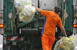 Ein Arbeiter wirft gelbe Säcke in ein Fahrzeug der Müllabfuhr. Foto: dapd