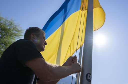 Daniel May, Mitarbeiter der Schweizerischen Eidgenossenschaft, hisst die Flagge der Ukraine vor der Ukraine-Wiederaufbaukonferenz URC. Foto: Pascal Lauener/KEYSTONE/dpa