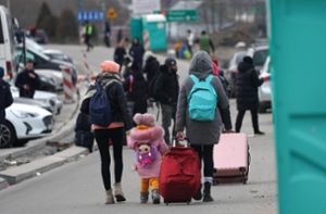 Flüchtlinge gehen nach dem Grenzübertritt aus der Ukraine eine Straße entlang. Foto: Smith/dpa