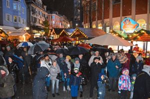 Mit Regenschirmen in der Hand verfolgen die Besucher vor der Bühne am City-Rondell  die diesjährige Eröffnung des Schwenninger Weihnachtsmarkts. Foto: Kratt
