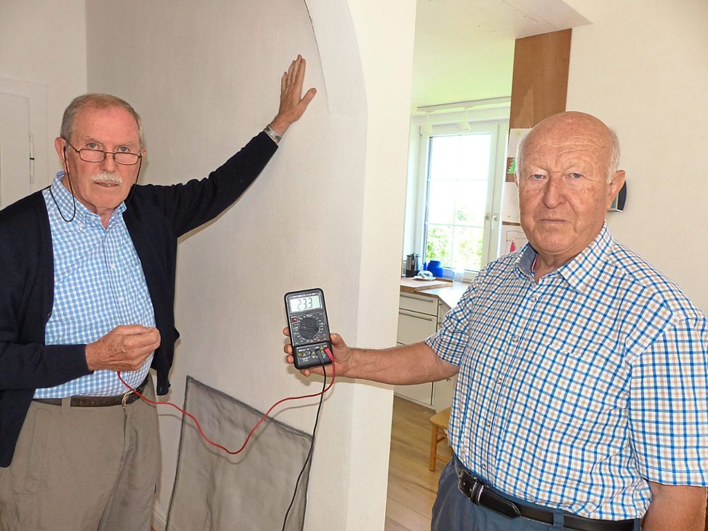 Siegfried Blickle (links) und Hans Lambacher von der Bürgerinitiative Mobilfunk demonstrieren, wie man mit einem Messgerät  die Strahlung von elektrischen Leitungen in der Wand messen kann. Foto: Breitenreuter