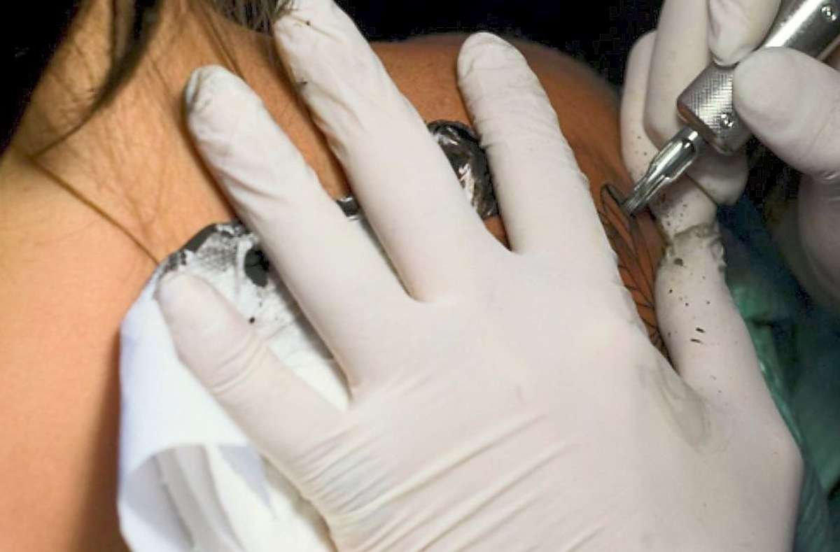 Ein Tätowierer sticht ein Tattoo. (Symbolfoto)