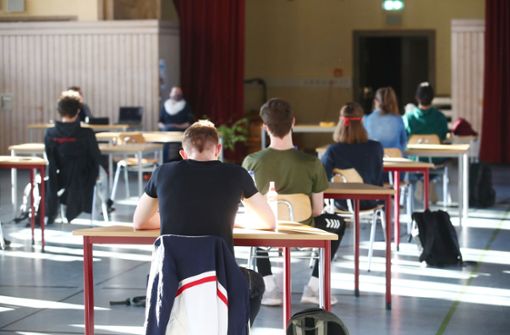 Schüler mit Mundschutz sitzen bei der Prüfungsvorbereitung fürs Abitur in einer zum Schulraum umfunktionierten Turnhalle. Foto: picture alliance/dpa/Bodo Schackow