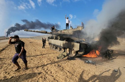 Palästinenser jubeln nach dem Großangriff der Hamas auf Israel auf einem zerstörten israelischen Panzer. Foto: dpa